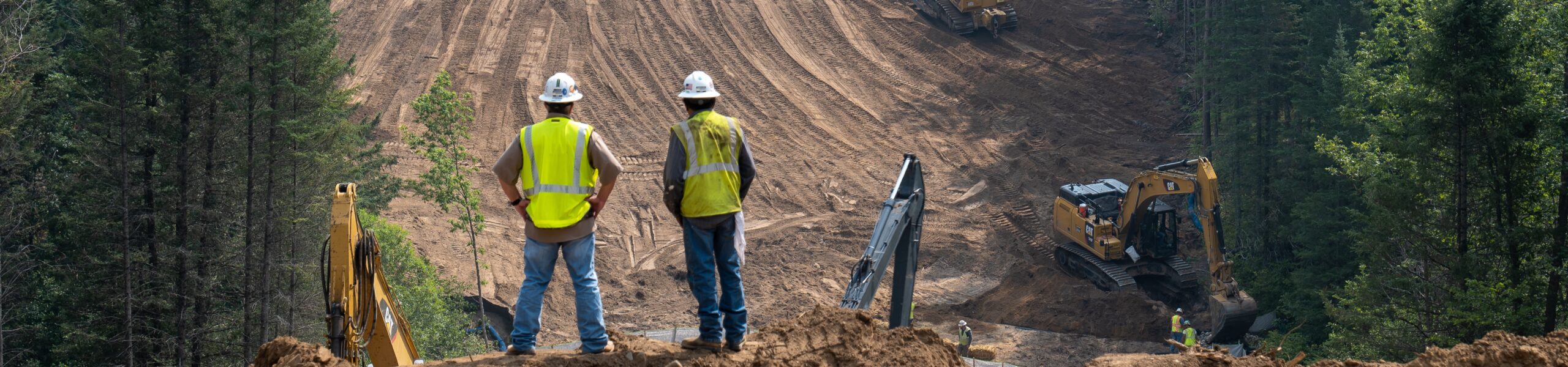 CASS CO, MN - 6 AUG 2021: Enbridge Line 3 Oil Pipeline Construction Site in Minnesota forest with excavators and bulldozers covering the installed pipe. Foreground is intentionally out of focus